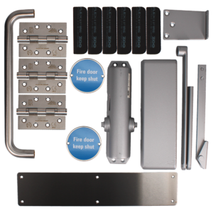 Assorted fire door hardware laid out: hinges, door closer, latch plates, and blue 'Fire door keep shut' signs on a metal background.